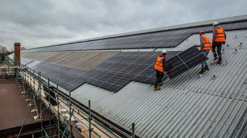 Staff standing on a depot roof installing solar panels